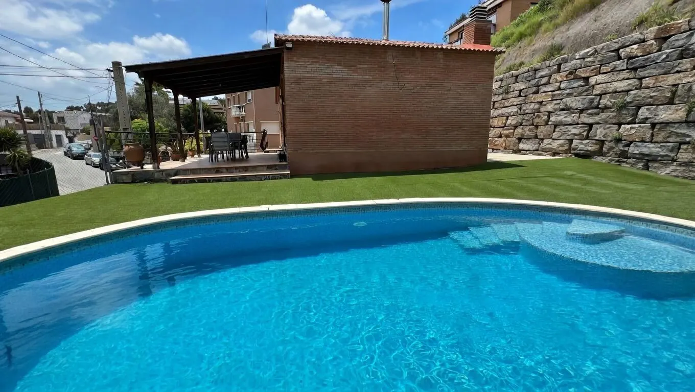 Jardín con piscina privada y fachada de obra vista